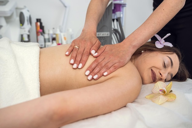 Female therapist doing massaging on a female patient back in the spa