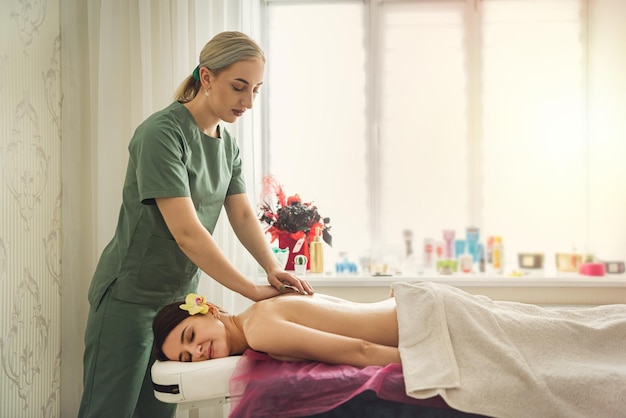 Female therapist specialist makes anticellulite massage on back woman client at spa salon