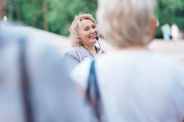 Female tour guide with a microphone standing among a group of tourists