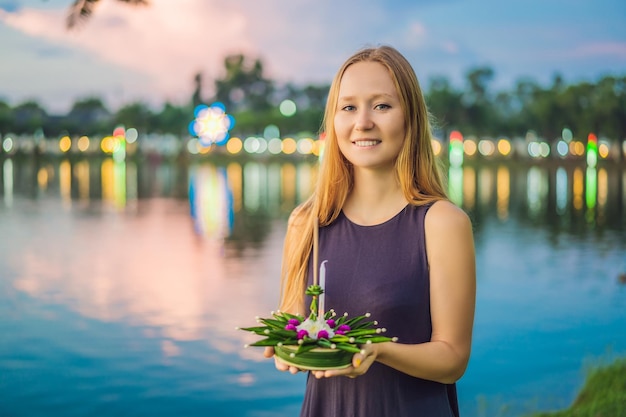 A female tourist holds the loy krathong in her hands and is about to launch it into the water loy