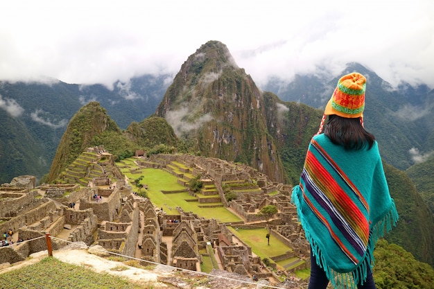 Female tourist looking at the famous ancient Inca ruins of Machu Picchu, Cusco region, Peru