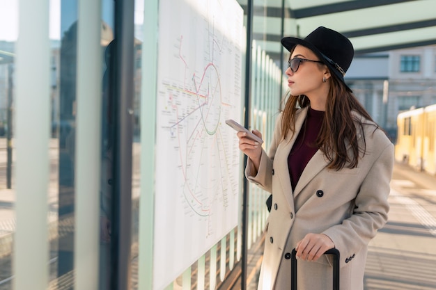 Female tourist looking the routes map at the bus stop.