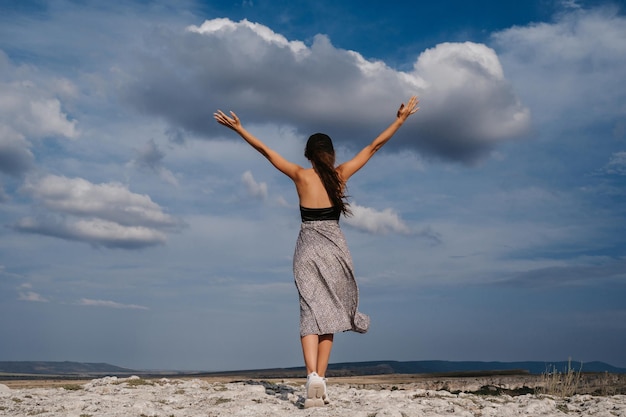 A female tourist standing with her hands up on the top The girl greets the sun