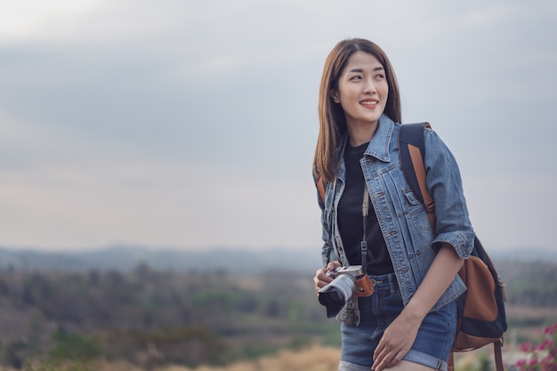 Female tourist with backpack and camera in countryside