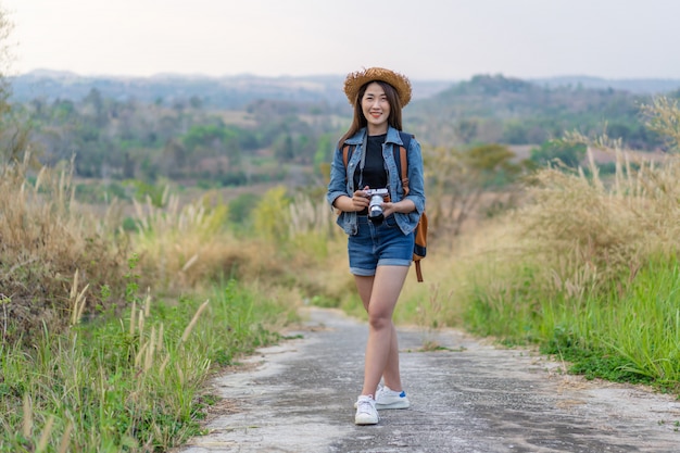 Female tourist with backpack and camera in countryside