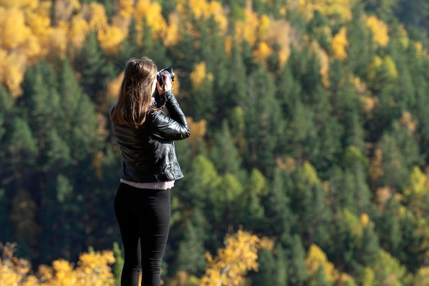 A female travel photographer photographs nature and the forest the autumn landscape of the taiga freedom and outdoor travel lifestyle