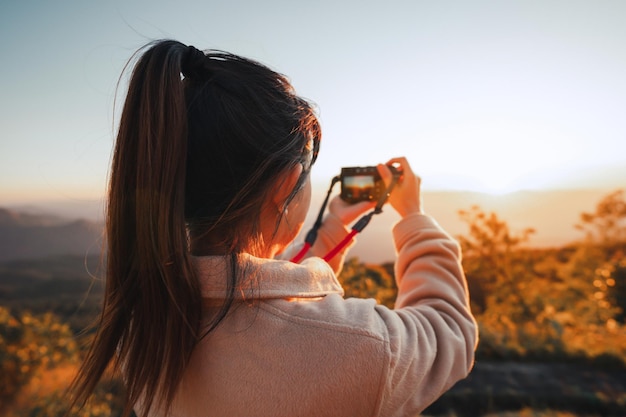 Female traveler photographing take photo view of sunset at mountain with camera