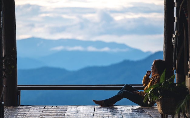 A female traveler sitting and looking at a beautiful mountain and nature view before sunset