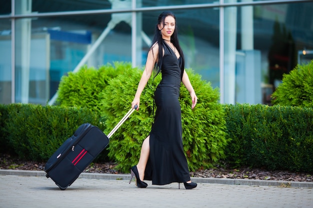 Female traveler walking with their luggage near airport