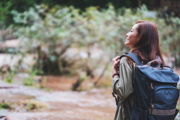 A female traveler with backpack walking  by mountain stream for hiking concept