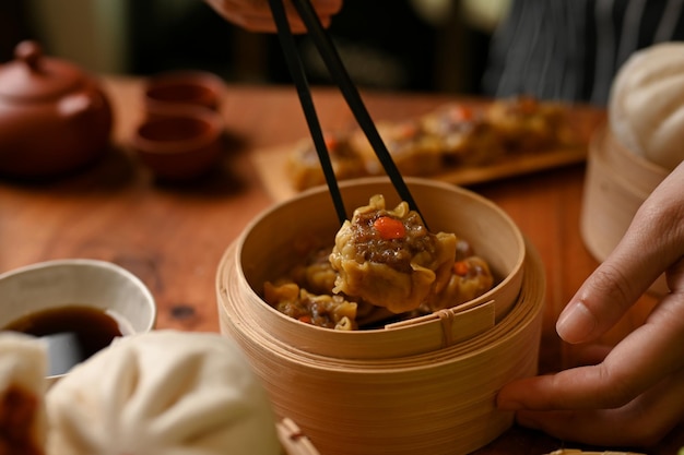 Female using chopsticks eating delicious steamed pork dumpling