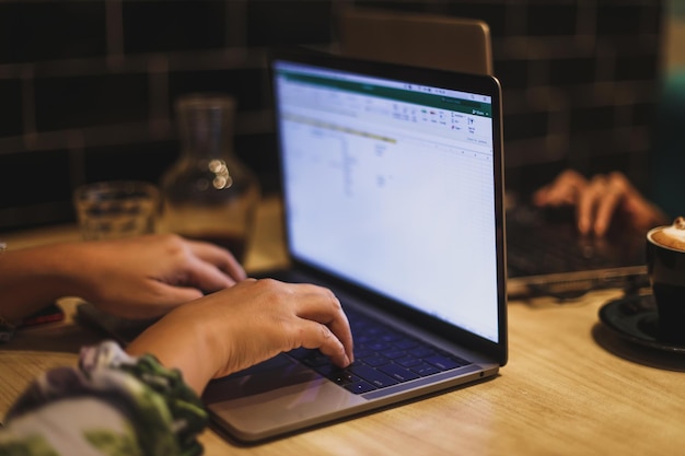 Female using her laptop at a cafe. Closeup shot of woman sitting at a table with a cup of coffee and