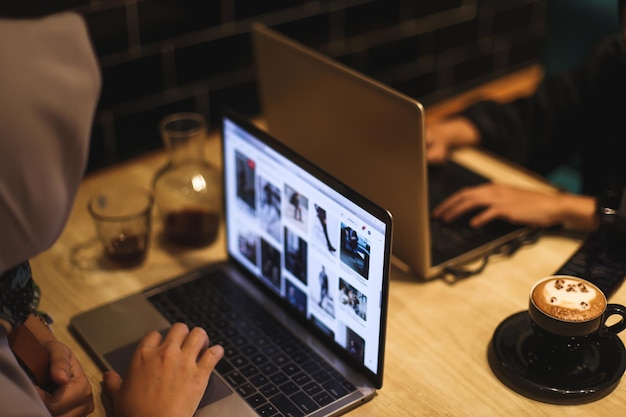 Female using her laptop at a cafe. Closeup shot of woman sitting at a table with a cup of coffee and