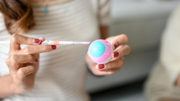 Female using paint brush painting on an Easter egg in her living room Holiday Traditional activity