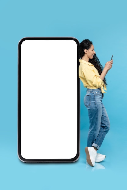 Female Using Smartphone Leaning On Huge Phone Screen Blue Background