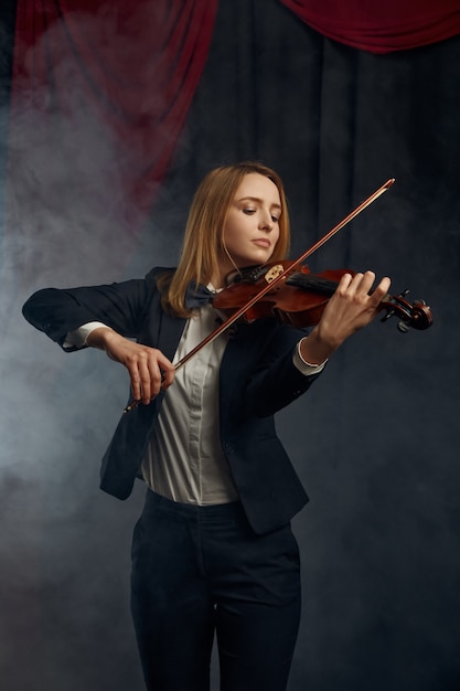 Female violonist with bow and violin, performance on stage. Woman with string musical instrument, music art, musician play on viola