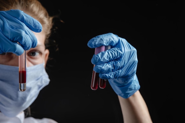 A female virologist works with blood tubes against a black background a nurse is holding blood tubes