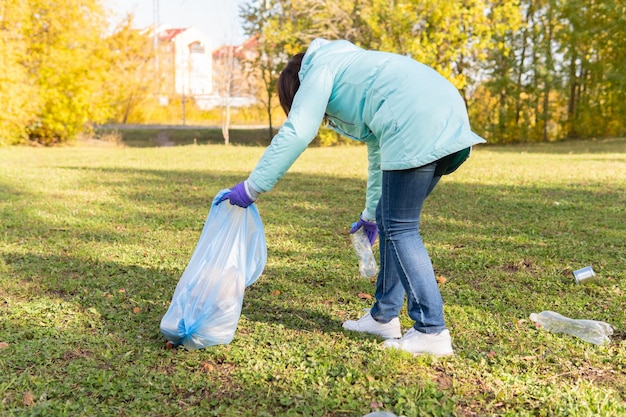 A female volunteer cleans plastic garbage in nature