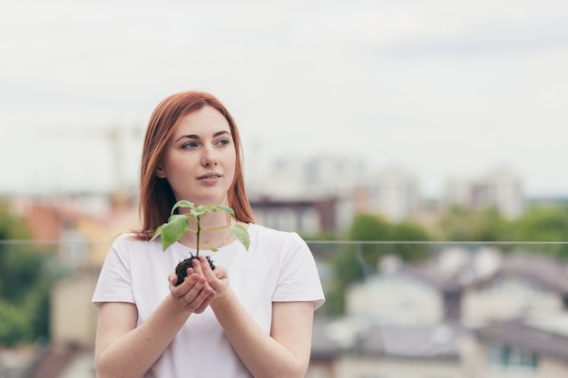 Female volunteer holds in her hands a seedling of a flower tree