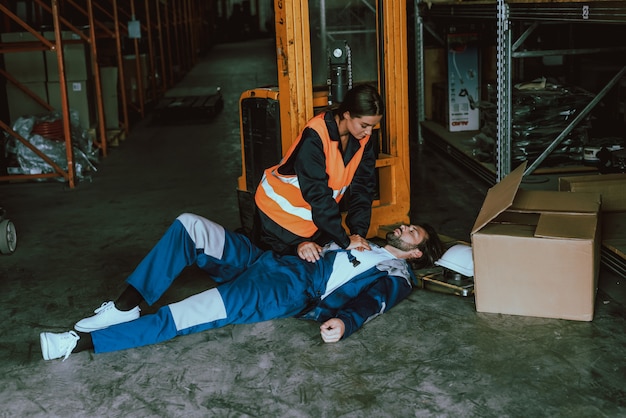 Photo female warehouse worker providing first aid to man