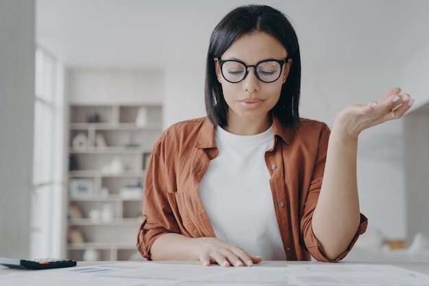 Female wearing glasses calculating expenses planning household budget for saving money at home