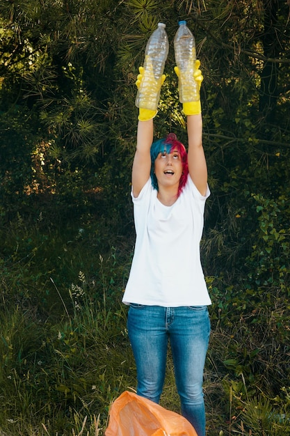 Female wearing gloves holding recyclable plastic bottles - plastic pollution concept