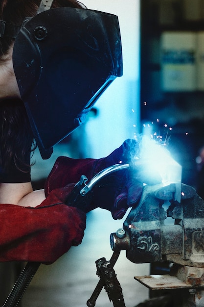 Female welding a metal piece in the garage