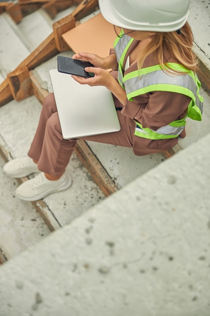 female with a computer on her knees sitting on the stairs