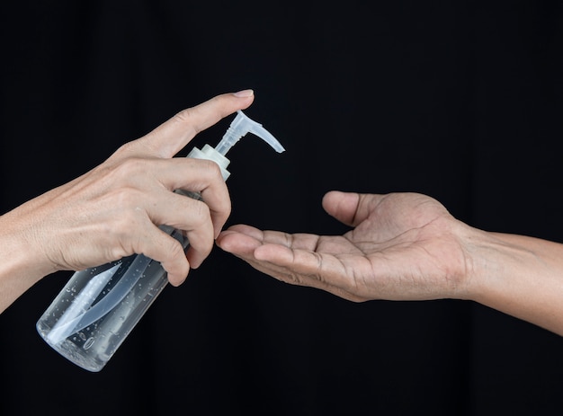 A female with a hand sanitizer push gel to male hand.