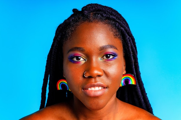 Female with rainbow makeup and long eyelashes in blue studio baclground