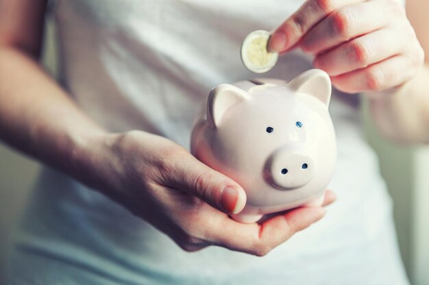 Female woman hands holding pink piggy bank and putting money Euro coin Saving investment budget business wealth retirement financial money banking concept