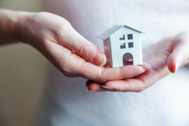 Female woman hands holding small miniature white toy house Mortgage property insurance dream moving home and real estate concept