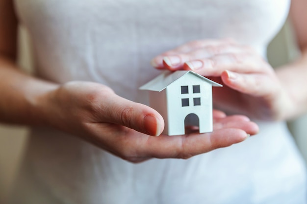 Female woman hands holding small miniature white toy house