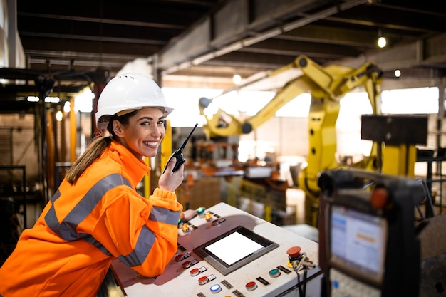 Female worker controlling industrial manufacturing process and parts assembly in factory