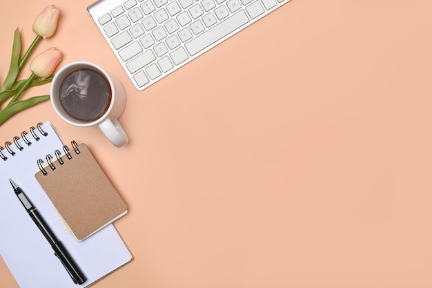 Female workspace with notebook coffee cup keyboard and pink tulips