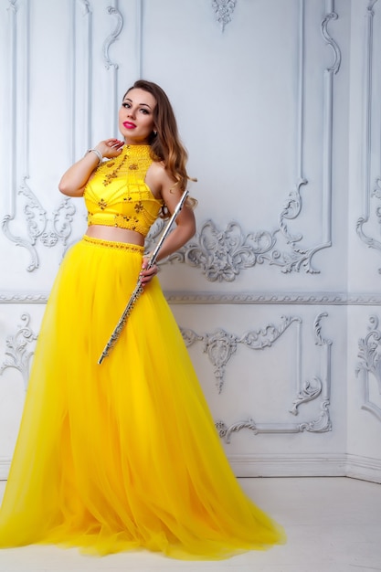 Female in yellow dress with flute on white