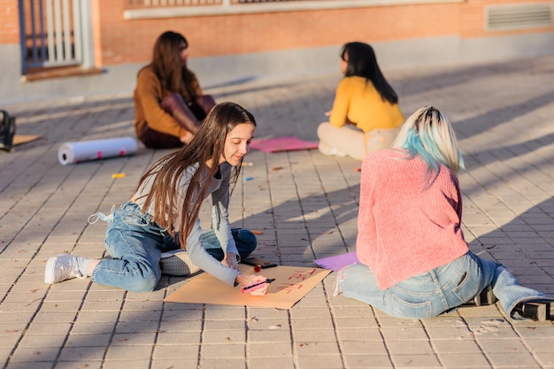 Females drawing on poster outdoors