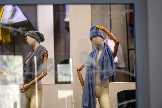 Females fashion store mannequins with hats and scarves details of shop window selective focus