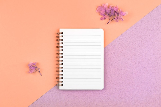 Femenine workspace concept with blank white notebook mockup with colorful dried flowers on a desktop top view and flat lay photo