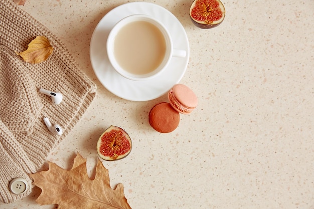 Feminine casual lifestyle white sweater and headphones Aesthetic coffee time among fall leaves macaroons and figs with copy space