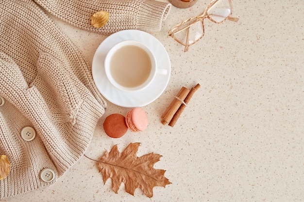 Feminine fall cozy home lifestyle sweater glasess Atmospheric coffee time among oak leaves cinnamon sticks macaroons Copy space