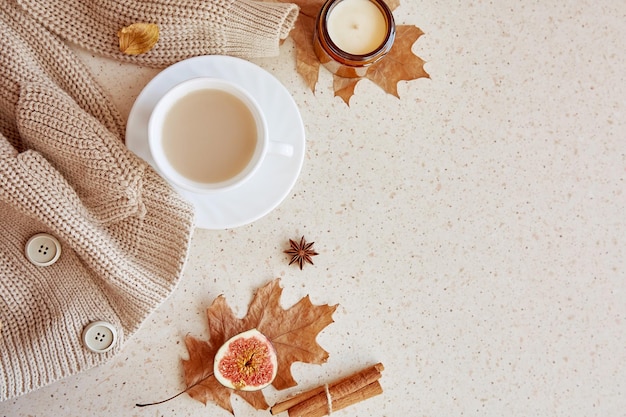 Feminine fall sweater among fragrance leaves candle and cinnamon sticks Autumn aesthetic coffee time Copy space