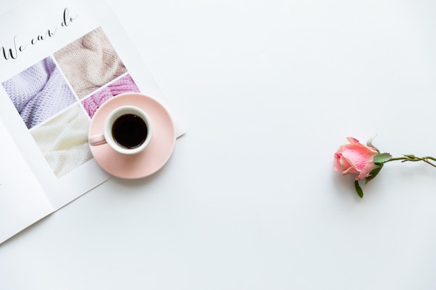 Feminine modern home office desk with pastel pink notebook glasses coffee cup wildflowers