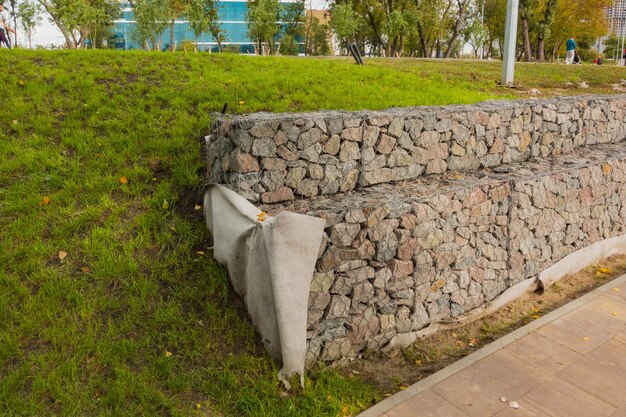 A fence wall from steel mesh with stones was installed in the park Grunge Rough Textured Stacked Technology Decorative Galvanized Brick Frame Gray Exterior Detail Gabion New Texture