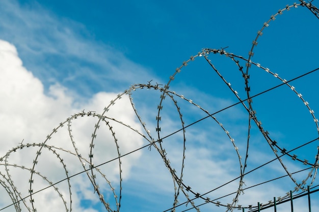 A fence with barbed wire on a blue sky background Restricted passage area