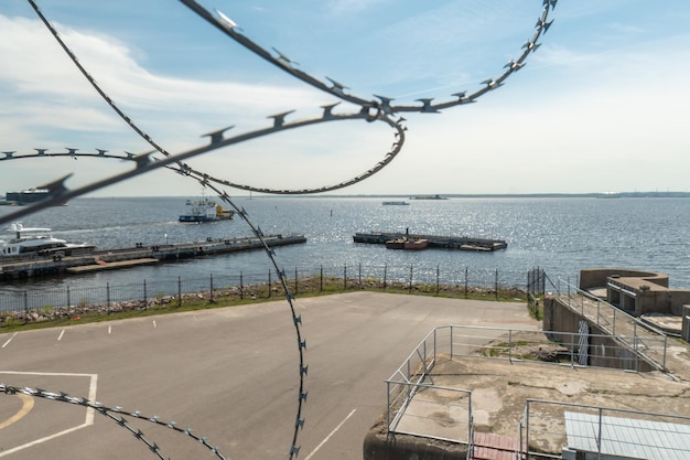 A fence with barbed wire is in front of a body of water.