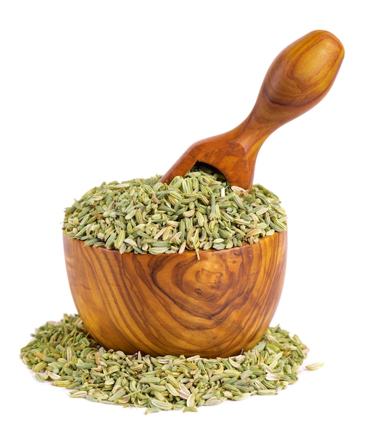 Fennel seeds in wooden bowl and spoon isolated on white background Green fennel grains Spices and herbs