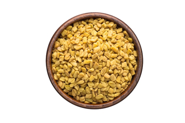 Fenugreek seed spice in wooden bowl, isolated on white background. Seasoning top view