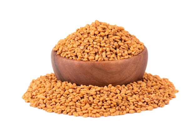 Fenugreek seeds in wooden bowl, isolated  Shambala, helba seeds.