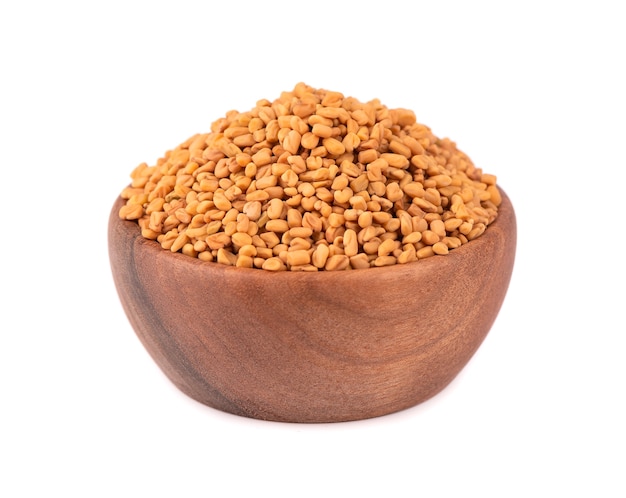 Fenugreek seeds in wooden bowl, isolated  Shambala, helba seeds.